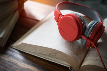 Open book redy for study with a pair of red headphones lying on it playing gentle ambient music designed to support focus and concentration